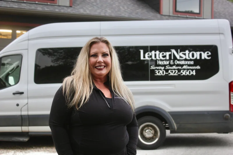 Karen, Office and Customer Coordinator at LetterNstone, standing in front of the company van