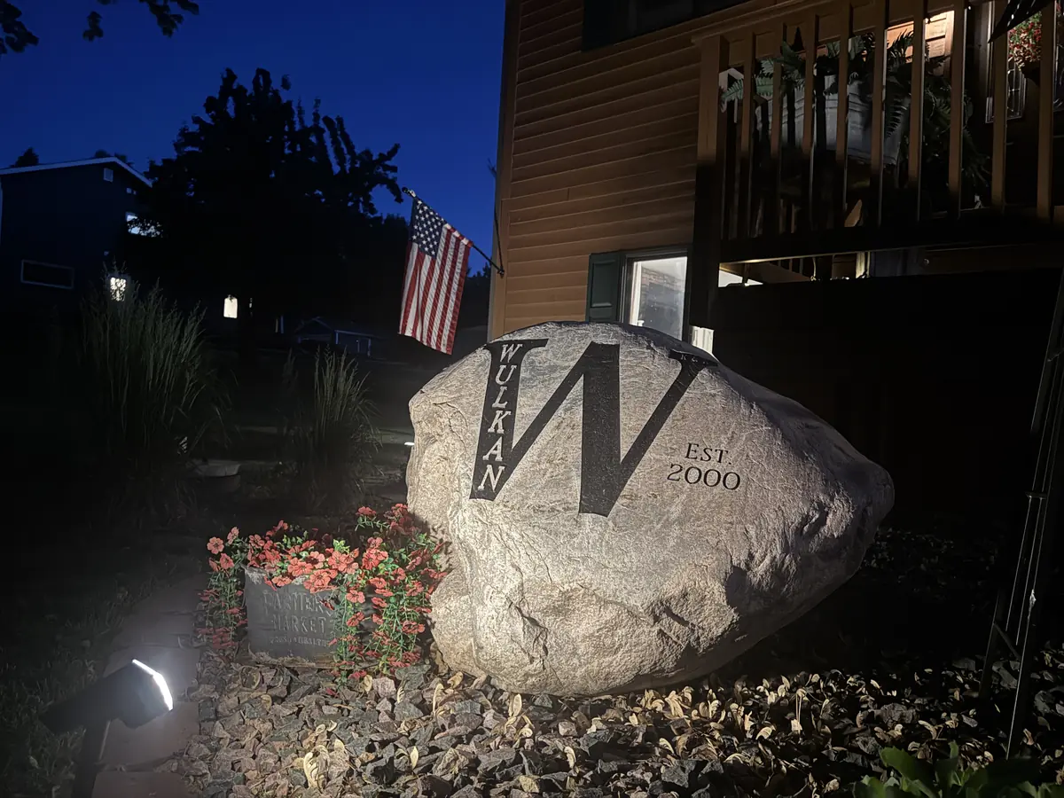 Wulkan K&K Est. 2000 — custom engraved granite yard rock by LetterNstone, illuminated at night
